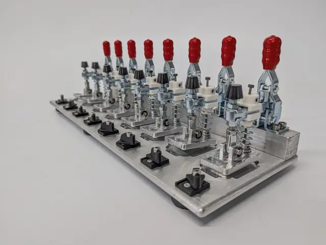 Custom automation fixture with rows of toggle clamps on a machined aluminium plate