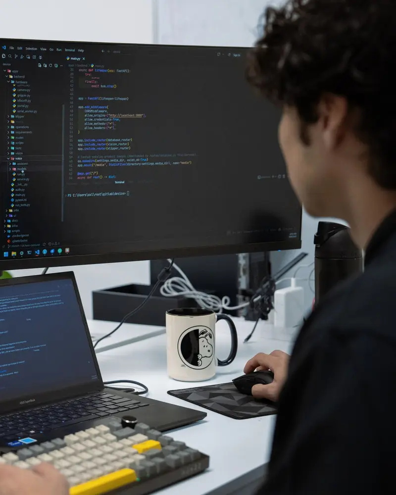 Axl en train de coder à un poste de développement à deux écrans